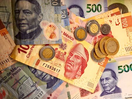 Many mexican pesos bills spread randomly over a flat surface