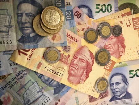 Many mexican pesos bills spread randomly over a flat surface
