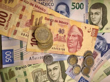 Many mexican pesos bills spread randomly over a flat surface
