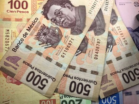 Many mexican pesos bills spread randomly over a flat surface