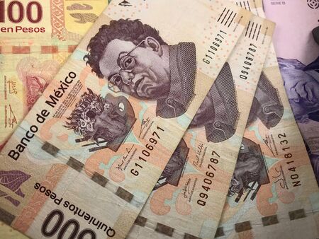 Many mexican pesos bills spread randomly over a flat surface