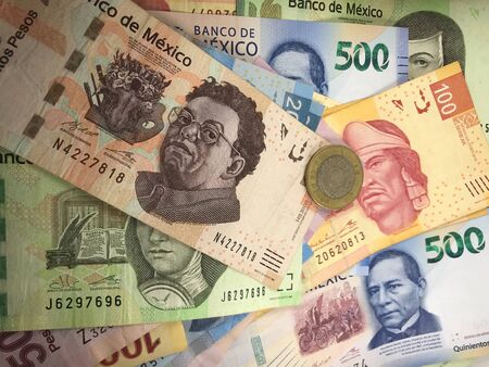 Many mexican pesos bills spread randomly over a flat surface