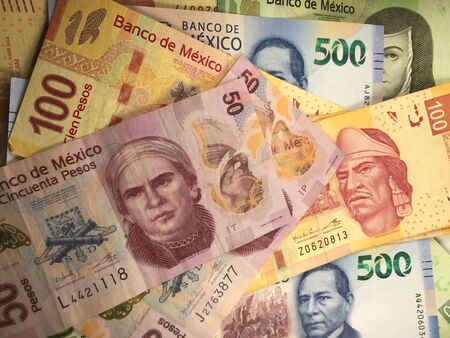 Many mexican pesos bills spread randomly over a flat surface