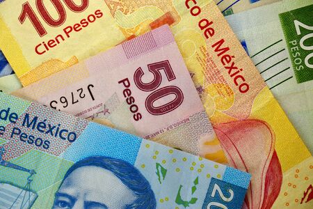 Many mexican pesos bills spread randomly over a flat surface Stock Photo