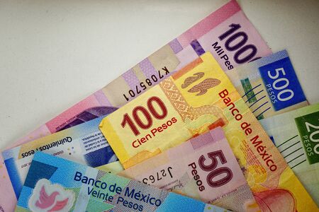 Many mexican pesos bills spread randomly over a flat surface