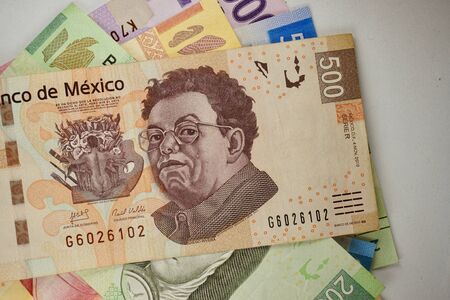 Many mexican pesos bills spread randomly over a flat surface