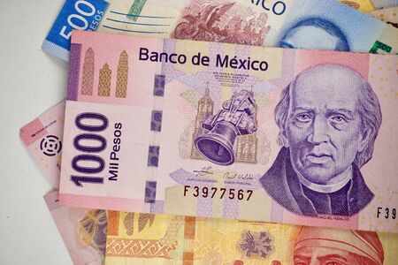 Many mexican pesos bills spread randomly over a flat surface