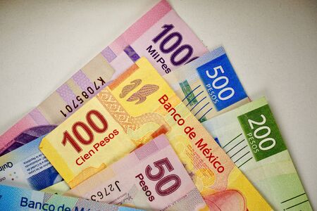 Many mexican pesos bills spread randomly over a flat surface