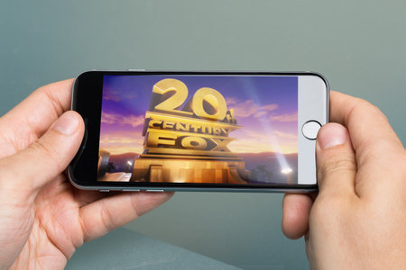 ベルリン ドイツ 10 月 10 日 2014 20 世紀フォックス映画社のロゴを持つ Apple Iphone6 を保持している手の画像をトリミングします 20 世紀フォックス映画株式会社六つの主要な映画スタジオの一つであり 5 月 31 日 結成1935 の写真素材