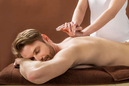 Massage: Портрет молодой человек получают массаж спины в спа красоты Фото со стока