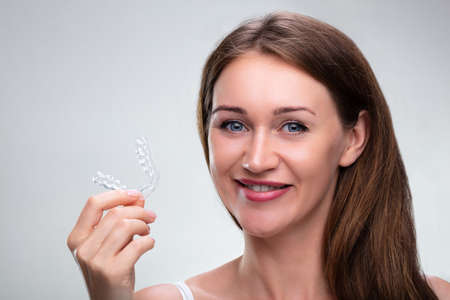 Close-up of a woman's hand putting transparent aligner in teeth Zdjęcie Seryjne