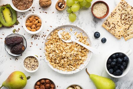 Składniki na zdrowe śniadanie pełnoziarniste śniadanie w orzechy, owoce, jagody, płatki kukurydziane, muesli, super food, quinoa, siemię lniane, jagody, winogrona. na jasnym tle. widok z góry Zdjęcie Seryjne