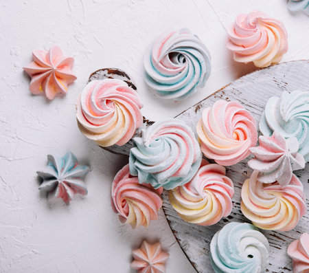 Multicolored meringue on wooden tray top view