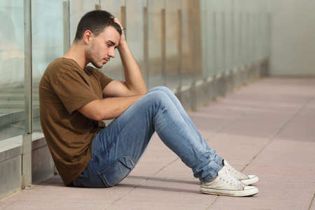sad lonely: Teenager boy worried sitting on the floor with a hand on the head