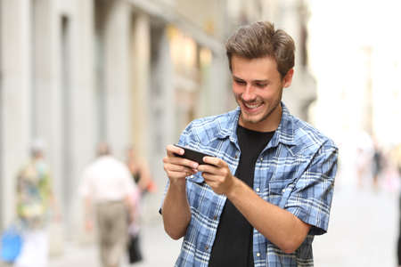 Happy man playing game with a smart phone in the street - 45076850