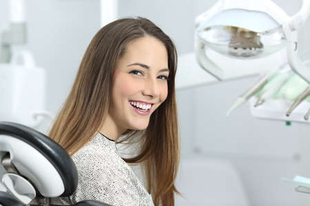 Dentista paciente satisfecho que demuestra su sonrisa perfecta después del tratamiento en una caja clínica con los equipos médicos en el fondo Foto de archivo - 73044893
