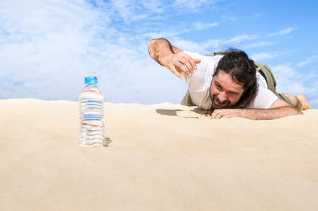 thirsty man in the desert reaches for a bottle of pure water stock reaches