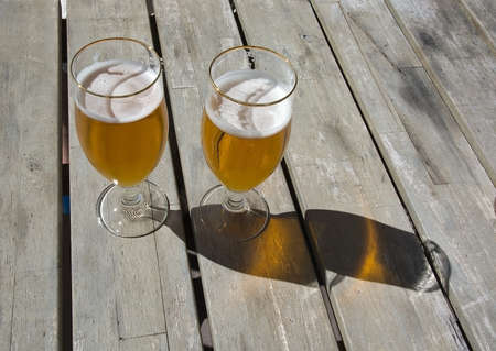 Dos cervezas en la mesa de madera rústica al aire libre en luz del ... Mesa con madera rústica en l