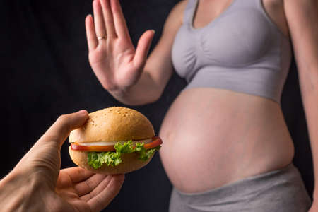 腹の妊娠中の女性は ハンバーガーから拒否します 妊娠中の体重の間に概念コントロール ファーストフードや不健康な食事 の写真素材 画像素材 Image