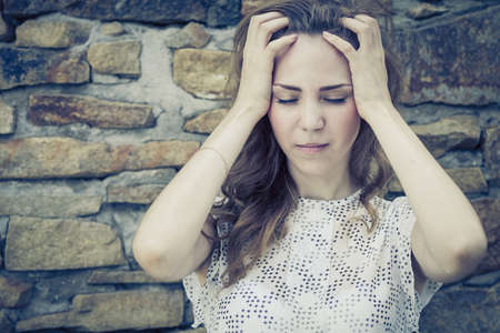 sad lonely: portrait of a beautiful young sad girl standing near the wall outdoors at the day time