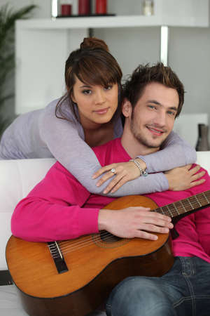 Woman beat guitar: Cặp vợ chồng trẻ ở trong nhà với một cây đàn guitar