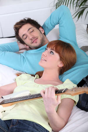 Woman beat guitar: Người phụ nữ trẻ và người đàn ông trẻ thư giãn chơi guitar