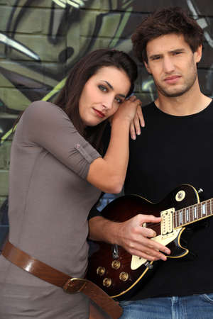 Woman beat guitar: Couple with guitar in front of painted wall Kho ảnh