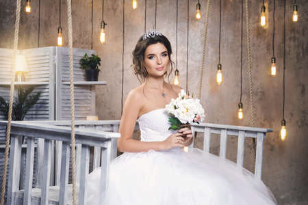 Young happy bride wearing beautiful lush dress in the room with a lot of light bulbs Banco de Imagens