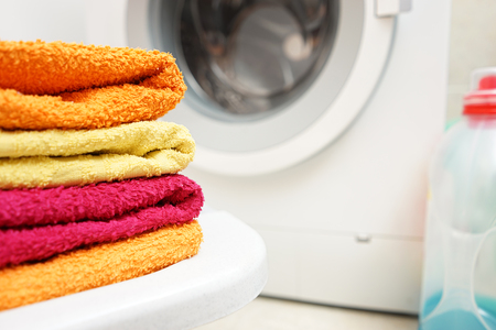 washed towels stacked with washing machine in background