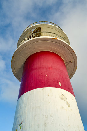 The cabo ortegal lighthouse in galicia with clouds in the background. low-angle shot. the lighthouse looks old and worn. in the sky you can see the silhouettes of some birds flying. Banco de Imagens