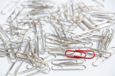 red color paper clip with another silver item on white background unique paper clip