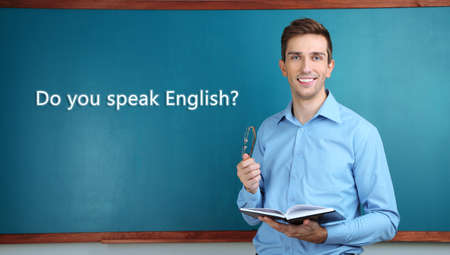 Young teacher near chalkboard in school classroom