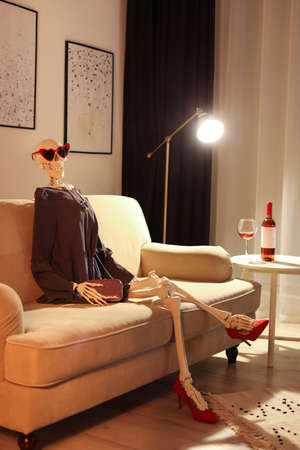 Skeleton in dress sitting on sofa at home Stock Photo