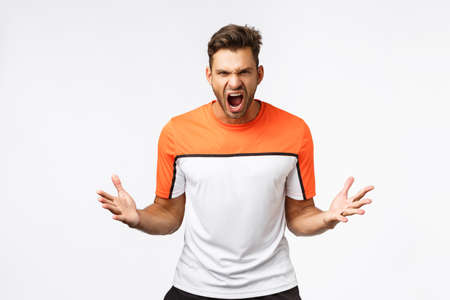 Aggressive, strong and determined, encouraged sportsman yelling and spread hands, grimacing making dangerous powerful expression as get head in game, prepare for fight or productive workout in gym