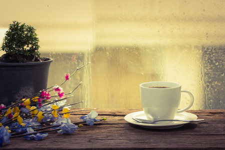 热气腾腾的咖啡杯在雨天窗口背景图片