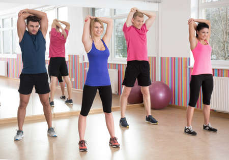 Fitness group exercising together at the gym Фото со стока