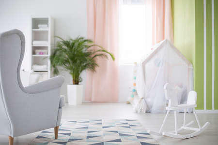 Geräumiges Weißes Babyzimmer Mit Sessel, Pflanze Und Krippe ... Geräumiges Weißes Babyzimmer Mit Sessel, Pflanze Und Krippe ...