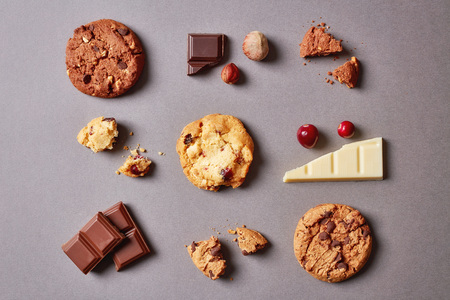 Different cookies with chocolate chips hazelnuts and cranberries on grey background top view