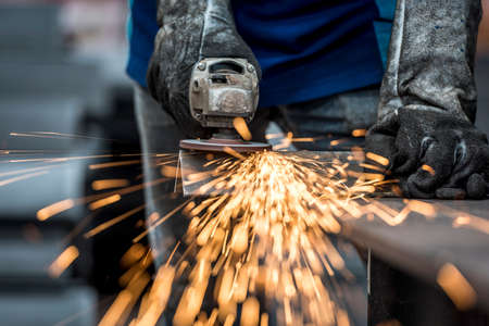 Industrial worker cutting metal with many sharp sparks Фото со стока