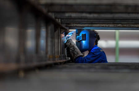 Worker with protective mask welding metal