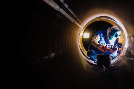 Workers welding work at night in the pipeline. Фото со стока