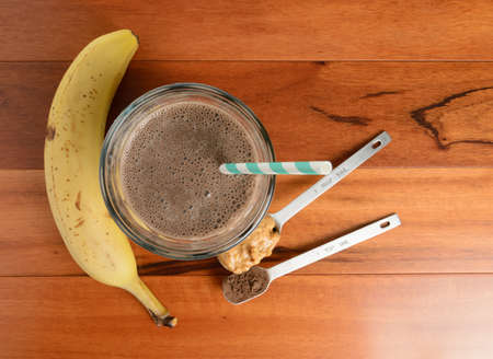 banana: Chocolate banana smoothie in a glass on a wooden table.