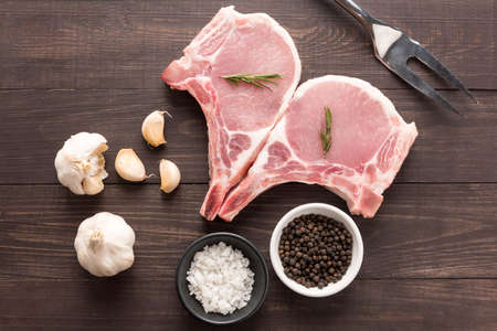 grilled pork: Top view raw fresh meat and salt, pepper, garlic, meat fork on wooden background.
