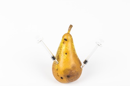 Close-up boring trace of a codling moth cydia pomonella, in a wormy pear. on white background. with syringe needle. concept non organic food and genetically modified organism. place to write