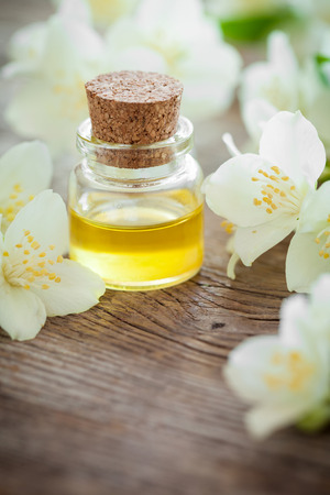 Bottle of essential jasmine oil and white jasmin flowers. Фото со стока