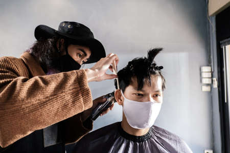 Asia Barber Shop Hair Cut Queuing Customer's Wearing Face Mask Prevention Business Wiedereröffnung nach Covonarirus Lockdown, Men's Hairstyling und New Normal Lifestyle Concept. Standard-Bild