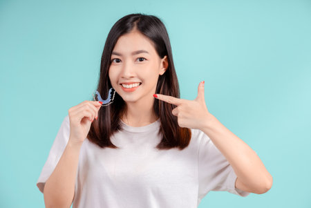 Dental Schönes Lächeln der jungen asiatischen Frau mit Halteklammern frohes Gefühl mit weißen Zähnen erhöht das Selbstvertrauen für gesunde auf blauem Hintergrund isoliert, glücklicher Teenager-Gesichtsausdruck. Standard-Bild