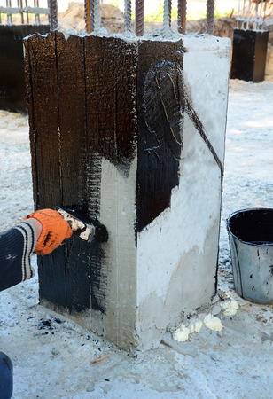 builder worker painting black coal tar on a brush a waterproofing