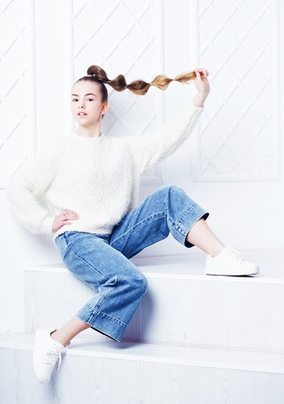 カジュアルな服を着たスタイリッシュな十代の少女がソファに座って ポージング の写真素材 画像素材 Image