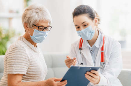 Doctor and senior woman wearing facemasks during coronavirus and flu outbreak. virus protection. covid-2019. taking on masks. Фото со стока